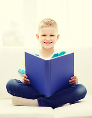 Image showing smiling little boy reading book on couch