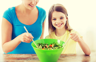 Image showing little girl with mother mixing salad in kitchen