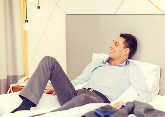 Image showing happy businesswoman lying in bed in hotel room