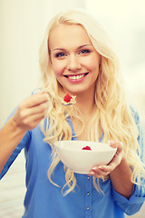 Image showing smiling woman with bowl of muesli having breakfast