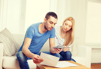 Image showing busy couple with papers and calculator at home