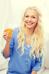 Image showing smiling woman with glass of orange juice at home