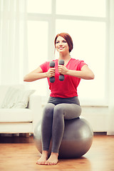 Image showing smiling redhead girl exercising with fitness ball