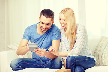 Image showing smiling couple with papers and calculator at home