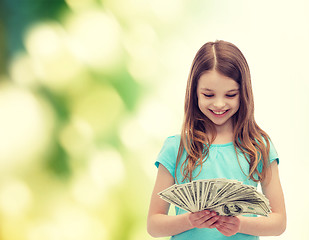 Image showing smiling little girl looking at dollar cash money