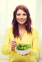 Image showing smiling young woman with green salad at home