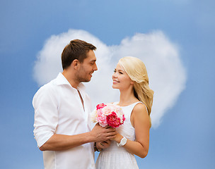 Image showing happy couple with flowers over heart shaped cloud