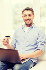 Image showing smiling man working with laptop and credit card