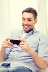 Image showing smiling man with smartphone at home