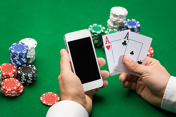 Image showing casino player with cards, smartphone and chips