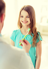 Image showing male doctor giving toothbrush to smiling girl