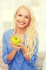 Image showing smiling woman with green apple at home