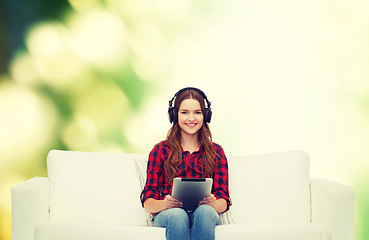 Image showing girl sitting on sofa with headphones and tablet pc