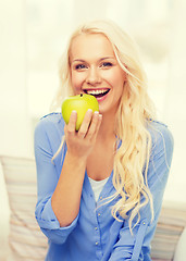 Image showing smiling woman with green apple at home