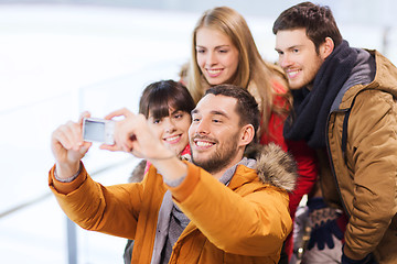 Image showing happy friends with camera on skating rink