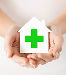 Image showing hands holding paper house with green cross