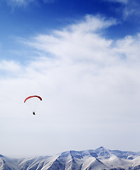 Image showing Parachutist silhouette of mountains in windy sky