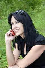 Image showing A smiling girl in a black dress with a red phone