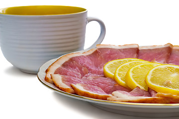 Image showing The dish with slices of ham and lemon on a white background.