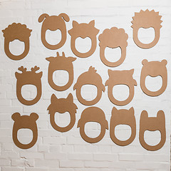 Image showing Set of cardboard masks on a white brick wall.