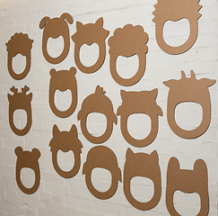 Image showing Set of cardboard masks on a white brick wall.