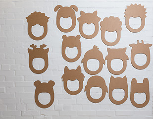 Image showing Set of cardboard masks on a white brick wall.