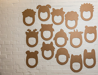 Image showing Set of cardboard masks on a white brick wall.