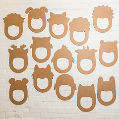 Image showing Set of cardboard masks on a white brick wall.