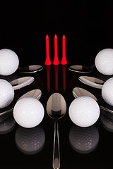 Image showing Teaspoons and golf equipments on the black glass table