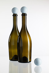 Image showing Empty wine bottles and golf balls on a glass desk