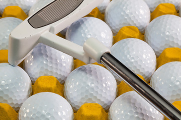 Image showing White golf balls in the yellow box and golf putter