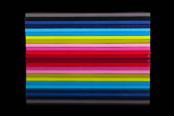 Image showing Twelve different color diaries on a black glass table