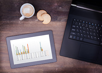 Image showing Tablet touch computer gadget on wooden table, graph