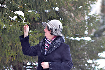 Image showing The woman in a hat and a sheepskin coat costs near a fir-tree in