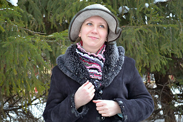 Image showing The woman in a hat and a sheepskin coat costs near a fir-tree in