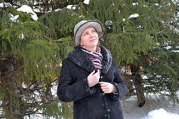 Image showing The woman in a hat and a sheepskin coat costs near a fir-tree in