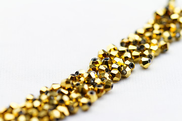 Image showing Beautiful golden glass beads closeup on white background