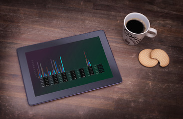 Image showing Tablet touch computer gadget on wooden table, graph