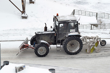 Image showing The tractor sweeps snow on the road.