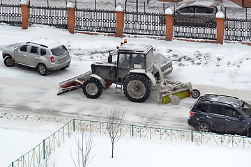 Image showing The tractor sweeps snow on the road.