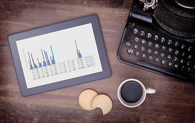 Image showing Tablet touch computer gadget on wooden table, graph