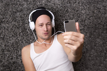 Image showing Attractive man with headphones makes selfie with his mobile