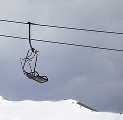 Image showing Chair lift and off-piste slope at gray windy day