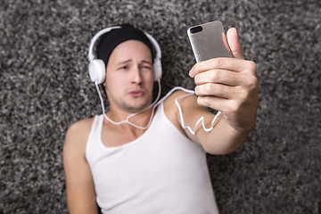 Image showing Attractive man with headphones unhappy to make selfie with his m
