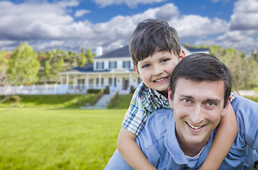 Image showing Mixed Race Father and Son Piggyback in Front of House