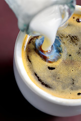 Image showing Milk poured into small cup of coffee