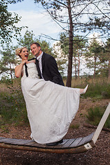 Image showing Young married couple is frivolous on a large swing.