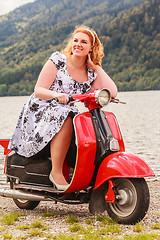 Image showing Red-haired beauty with overweight on a red scooter