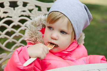 Image showing Child eating waffles with chocolate in park