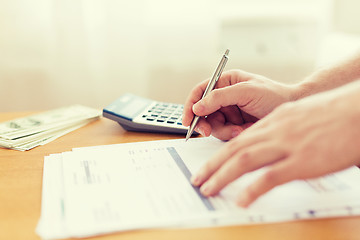 Image showing close up of man counting money and making notes